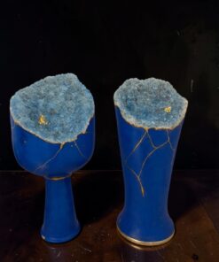 Two cobalt-blue goblets with jagged blue geode tops featuring gold vein accents, set on a dark wooden surface.