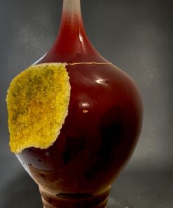 Glossy amber ceramic vase with a yellow, crusty chunk attached to its side.