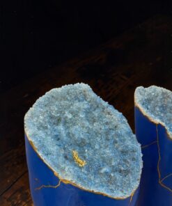 Blue ceramic vases topped with rough blue crystal geode halves, placed on a wooden surface.