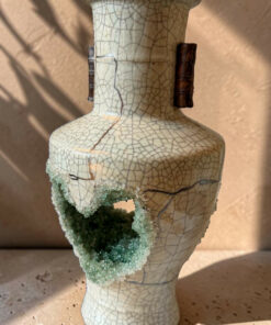 Beige crackle-glaze ceramic vase with brown handles; lower section is broken, exposing green-blue crystalline growth.