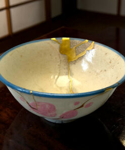 Ceramic bowl with a bright blue rim on a dark wooden table, with yellow ribbons draping over the edge.