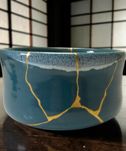 Blue ceramic bowl with gold streaks on a dark wooden table, background out of focus.