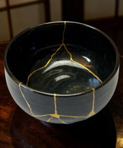 Close-up of a dark plastic bucket with yellow string draped over its rim on a wooden surface.