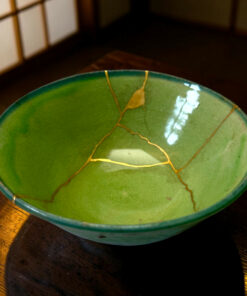 Green ceramic plate with gold crackle glaze, edges visible on a dark wooden table edge.