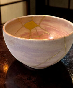 Ceramic bowl with pale lavender glaze and yellow crackle pattern, resting on a dark wooden table.