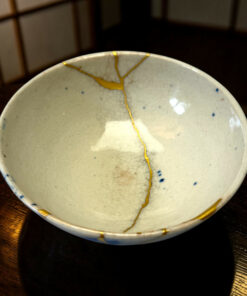 Close-up of a light ceramic bowl with yellow drizzle glaze, positioned on a dark wooden table.