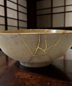 Close-up of a light ceramic bowl with string tied around its rim, resting on a dark wooden table.",