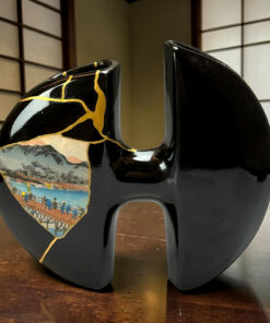 Two glossy black stools with gold crack patterns; the left stool shows a painted landscape with mountains and people against a wooden floor and shoji panels in the background.