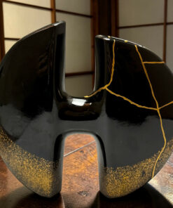 Close-up of two black high-heeled shoes with gold crackle detailing on a wooden floor.