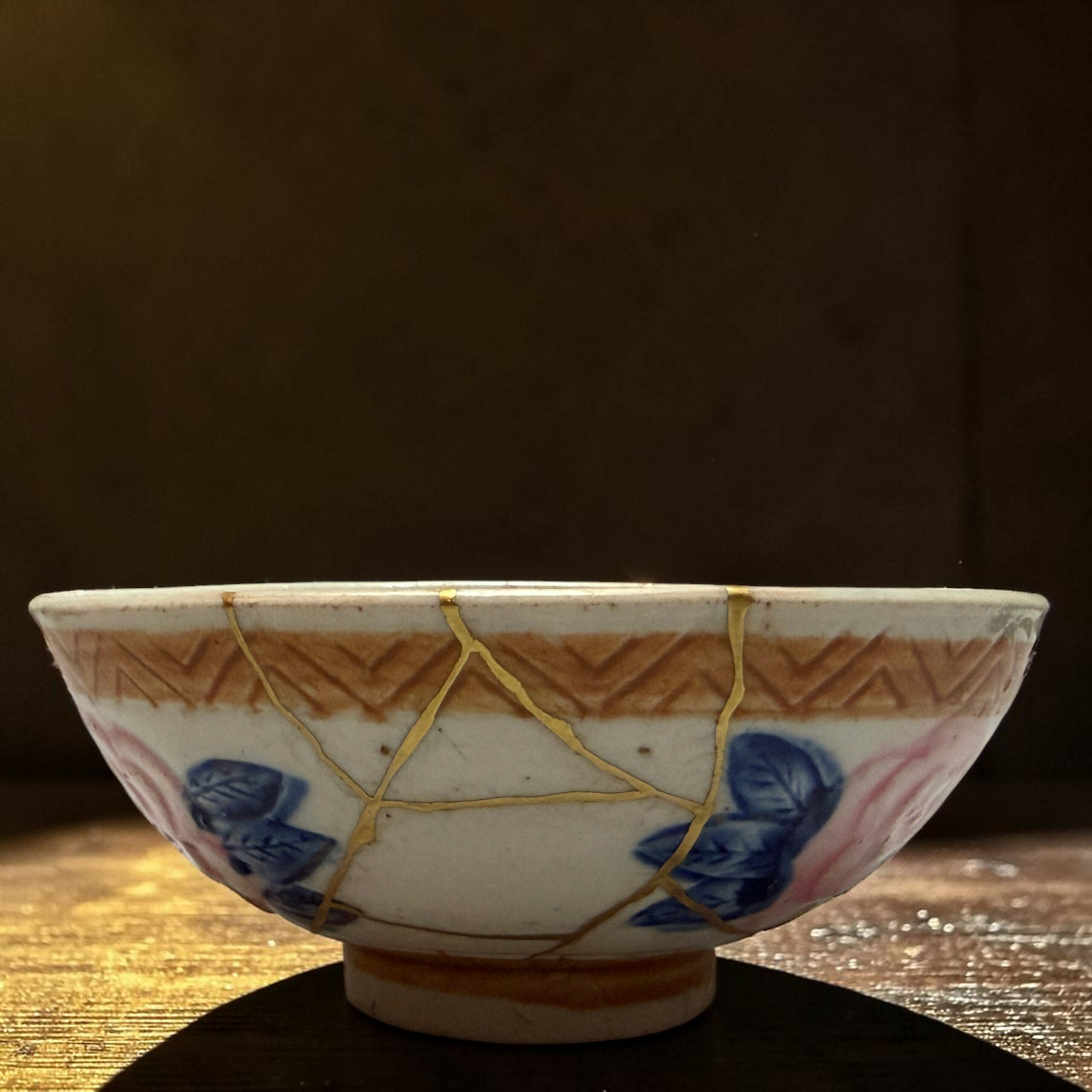 IMG_2500-Photoroom | Kintsugi by Myriam GREFF Decorative ceramic hanging planter with a beige rope lattice, blue floral patterns, resting over a wooden surface against a dark background.