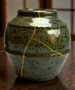 Close-up of a green-glazed ceramic vase with a crackled surface and a yellow string wrapped around its neck.