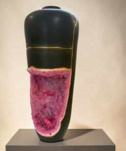 Close-up of a dark glossy sculpture leg with yellow seams, mounted on a gray pedestal, and a pink crystalline base showing along the leg edge.