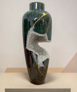Green ceramic vase with gold veining and a cluster of white crystals attached, displayed on a pedestal, museum-style.