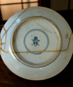Close-up of a light blue porcelain plate with a gold rim resting on a dark wooden table.
