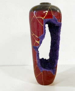 Ceramic red vase with purple textured glaze peeling in a wavy stripe, accented by fine gold lines against a white background