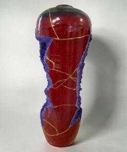 Close-up of a red popsicle with a purple sugar-coated rim and yellow cracks, against a white background.