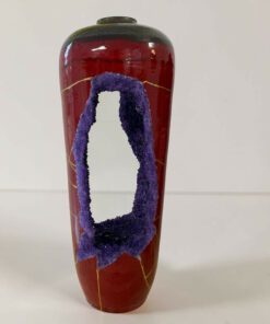 Tall red ceramic vase featuring a prominent purple textured loop design and thin yellow lines against a pale background.
