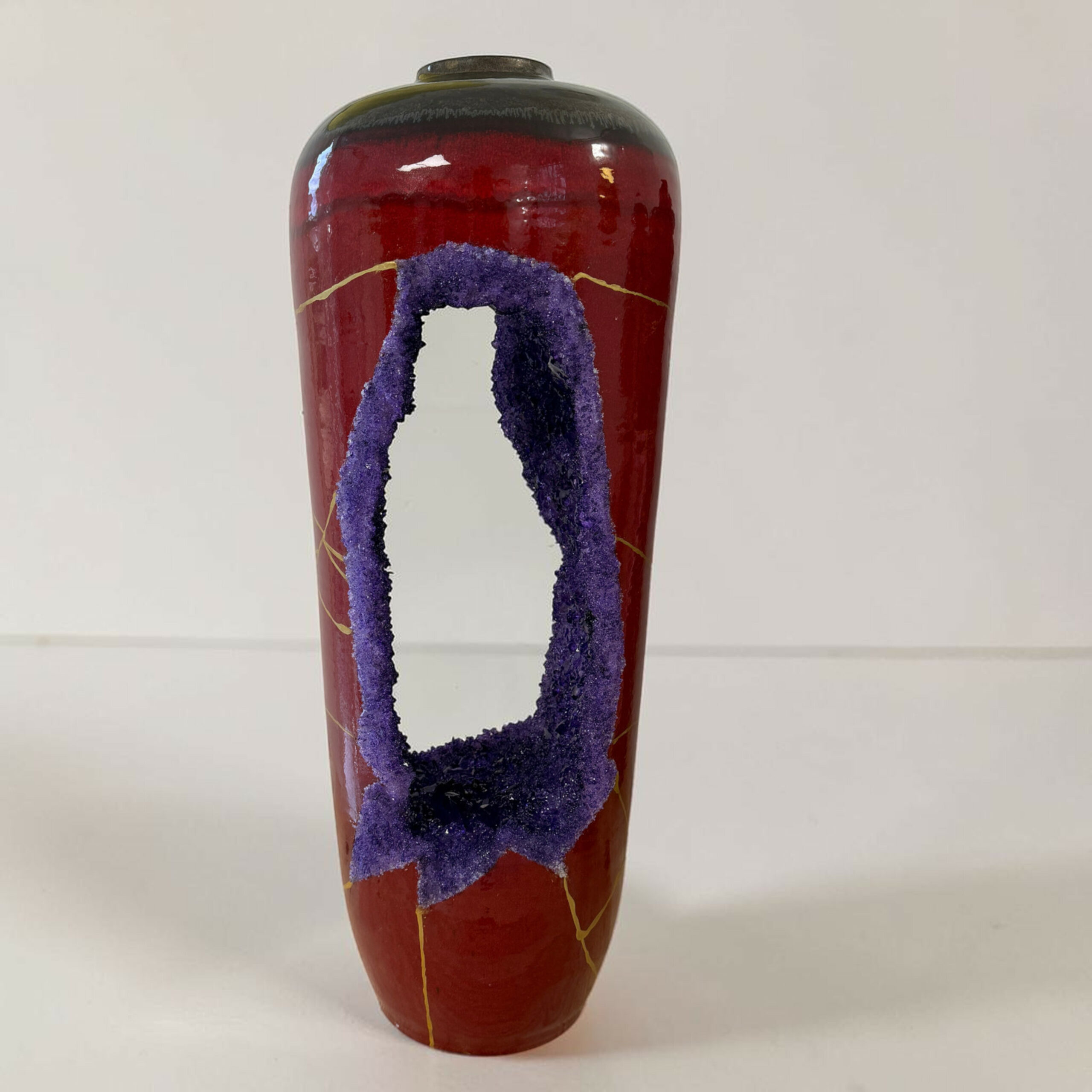 IMG_3241-Photoroom | Kintsugi by Myriam GREFF Tall red ceramic vase featuring a prominent purple textured loop design and thin yellow lines against a pale background.